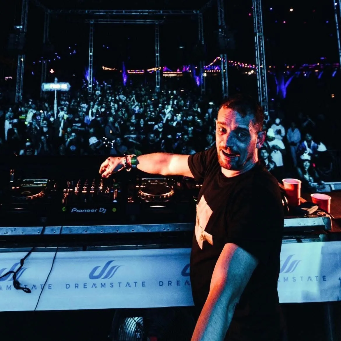 Carl Nicholson performing behind the DJ decks in front of a large festival crowd